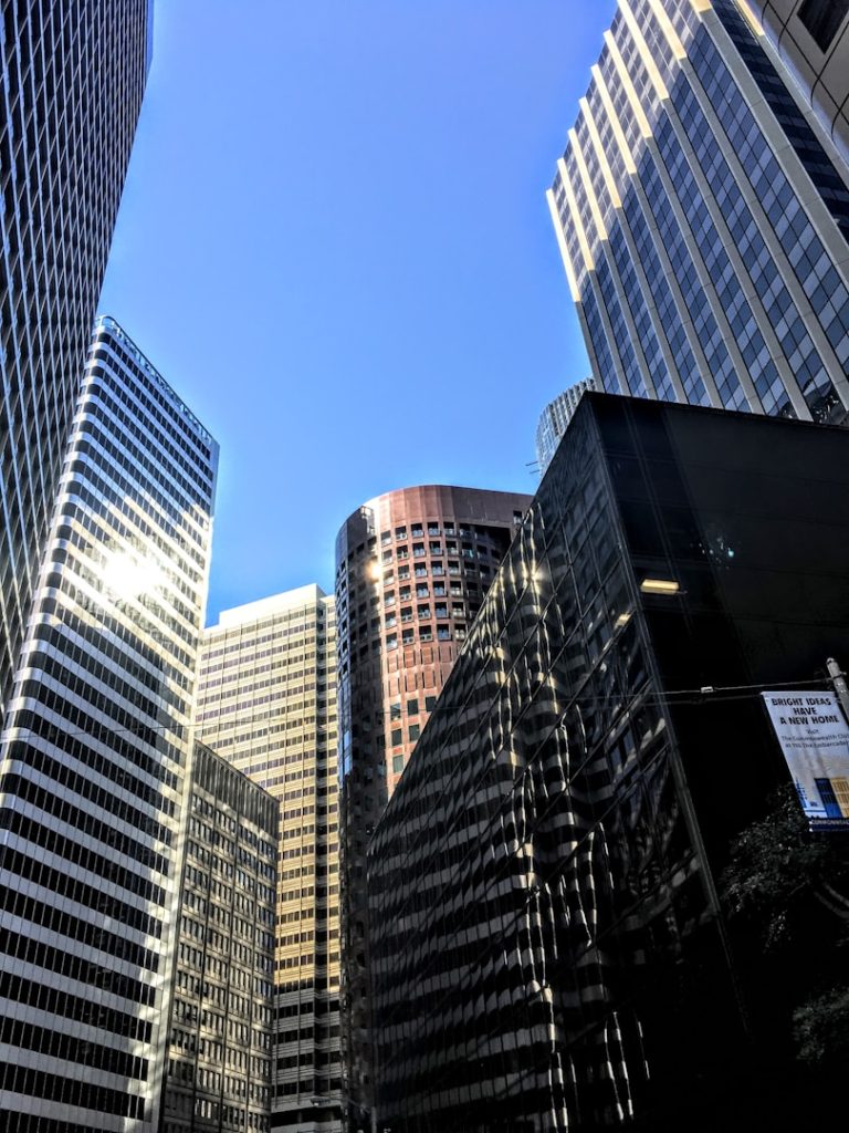 Modern skyscrapers reflecting sunlight against a clear blue sky.